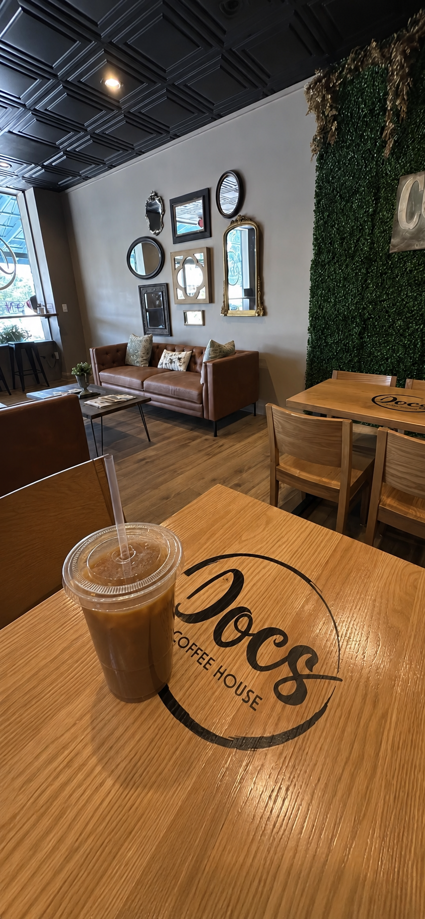 Iced coffee on a branded table inside the cozy Docs Coffee House interior
